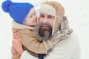 Winter, father and son play outdoor. Daddy and boy smiling and hugging. Happy son hugs his dad on winter holiday.