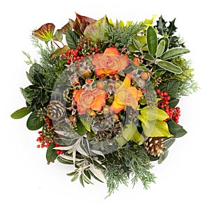 Winter festive floral arrangement. Flame colour roses, berries, greenery and leaves. On white background.