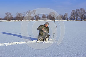 Winter fishing concept. Fisherman in action. Catching fish from snowy ice