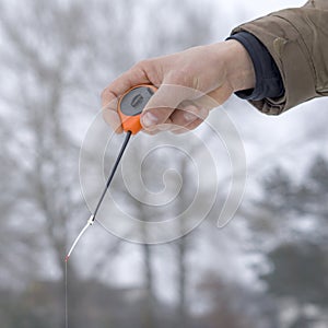 Winter fishing concept. Hand of fisherman with specialised rod above snowy ice