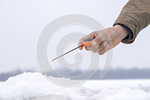 Winter fishing concept. Hand of fisherman with specialised rod above snowy ice photo