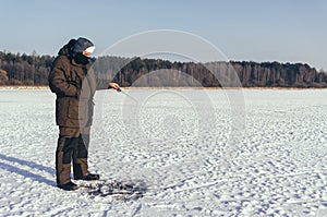 Winter fishing. Fisherman on the background of a frozen lake