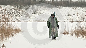 Winter fishing. Fisherman is going from winter fishing. Man in winter extreme clothing with fishing equipment and ice drill is wal