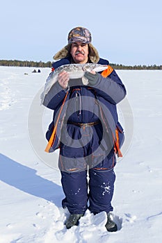 Winter fishing, fisherman holds trophy pike Esox lucius. space for copying text. Vertical photo