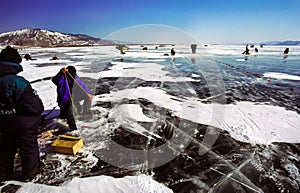 Winter fishing on the ice of Baikal. Fishermen are engaged in wi