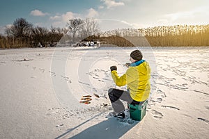 Winter fishing. Man in yellow catches a perch