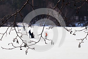 Winter fishing. River, lake near forest in ice. Blurred image of Anglers, Fishermens through tree branches, favorite men