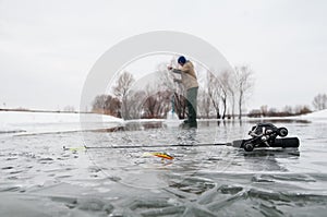 Winter fishing concept. Tackles on ice. Fisherman making the hole photo