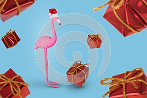 Winter flamingo in Santa hat and flying gift boxes. Merry Christmas and Happy New Year greeting card. Minimal Christmas and new