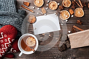 Winter flatlay with cozy home sweater, mittens, cup of black tea? blank greeting card and spices for mulled wine