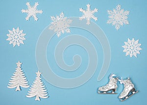 Winter flatlay with snowflakes and christmas tree ornaments on a blue background with space for copy