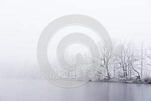 Winter fog on the bank of icy lake