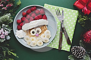 Winter food for kids. Christmas Santa pancake with raspberry and banana for children menu, green background, copy space