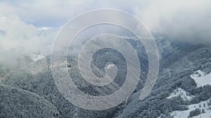 Winter forest from above. Winter mountains landscape. Trees covered with snow and frost. Fog above mountains. Winter