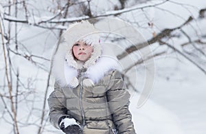 Winter forest. A little girl looking upset golding a snowball