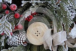 Winter frosted berries and greenery with large wooden button