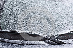 Winter frozen car window. An iced windshield of a car, a car covered with snow in a inter day.