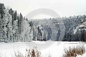 Winter frozen river with cliffs on a wooded shore