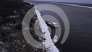 Winter frozen river. Clip.Cargo boats and bare trees on the shore taken from a bird's-eye view