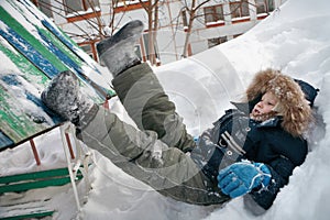 Winter fun. The boy lies in the snow and rejoices