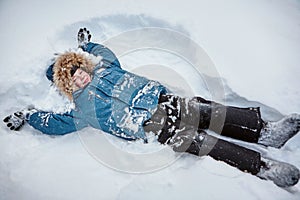 Winter fun. The boy is lying on the snow and rejoices
