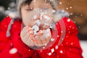 Winter fun. A child blows snow from the palms