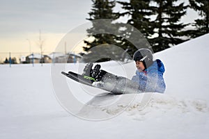 Winter Fun - Child Sledding/Tobogganing Fast Over Snow Ramp photo