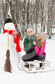 Winter fun with snowman in hat and red scarf mom and son