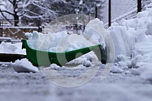 The Winter is gaining strength. A man with plastic shovel shoveling snow from driveways of home. Still snowing and snowing