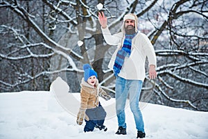 Winter game for happy family. Christmas Celebration holiday. Father and son play with snowball on winter white