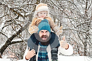 Winter game for happy family. Father giving son ride on back in park. Happy father and son - winter portrait.