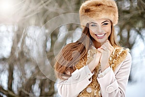 Winter girl portrait. Beautiful smiling woman in snowy park