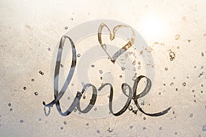 Winter glass with sun, inscription love and sign heart on frozen glass, Valentine`s Day card