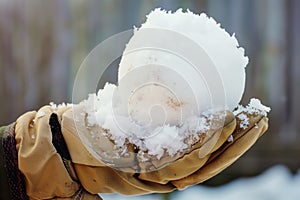 winter gloves holding a perfectly round snowball