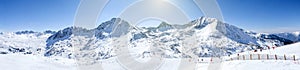 Winter high mountain chains landscape on a Sunny day. long ski slopes, lifts, skiers, snowboarders and snow-capped mountains in