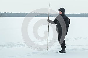 Winter hiker with birch walking stick exploring snowy frosty plain