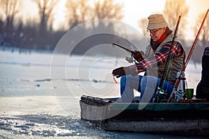 Winter hobby - fisherman fishing on the frozen lake
