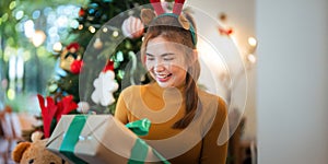 Winter holiday and concept happy Young woman surprise decorating Christmas tree and give a gift at home. concept