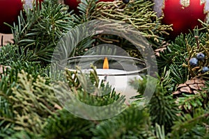Winter holiday decoration: fraser fir table wreath centerpiece with cones, juniper, Christmas tree balls and burning candle.