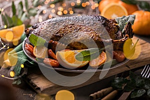 Winter Holiday table served for Christmas dinner with roasted duck, decorated with orange and herbs.  New year food