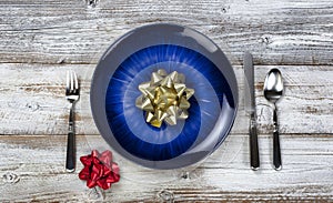 Winter holiday table setting with vintage cutlery, empty blue plate, fork, spoon and knife on white rustic wood table