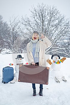 Winter holiday trip concept. Winter vacations. Happy young girl playing in fresh snow and making snowman at beautiful
