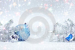 Winter holidays composition on white snow with christmas tree branches, decorative blue ball, silver glass star and drums toy