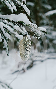 Winter holidays and decoration concept - christmas ball on fir tree branch covered with snow