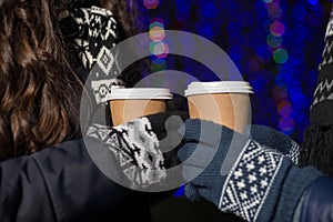 Winter holidays, hot drinks and people concept - happy young couple with coffee at christmas market in evening. Close up