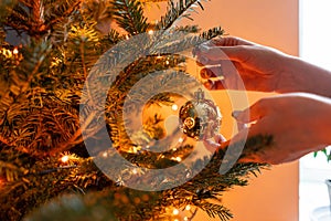 Winter holidays in a house interior. Happy young woman decorating christmas tree at home. Golden and white Christmas