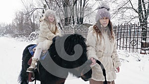 winter horse ride. horseback riding at winter. family horseback ride on snowy winter day. Happy cutie, little girl is