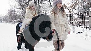 winter horse ride. horseback riding at winter. family horseback ride on snowy winter day. Happy cutie, little girl is