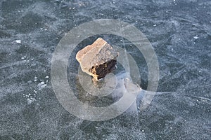 Winter ice with cracks under stone throw