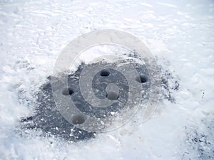 Winter ice fishing. Fishing rod for ice fishing. Hobbies, winter. Drilled holes in the ice for fishing